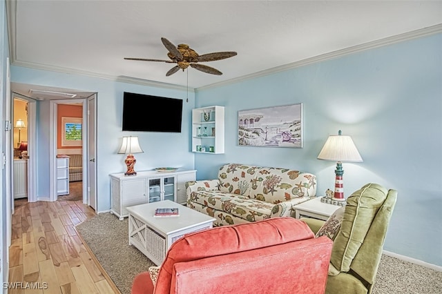 living area with ornamental molding, wood finished floors, a ceiling fan, and baseboards