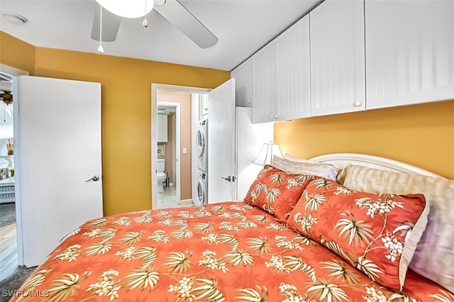 bedroom with stacked washer / dryer, ceiling fan, and ensuite bath