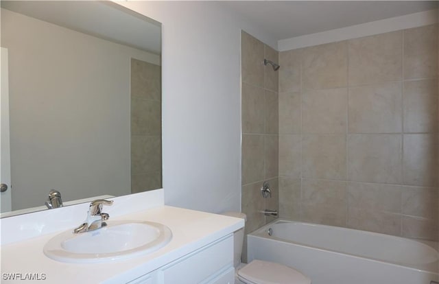 full bathroom with tiled shower / bath, vanity, and toilet