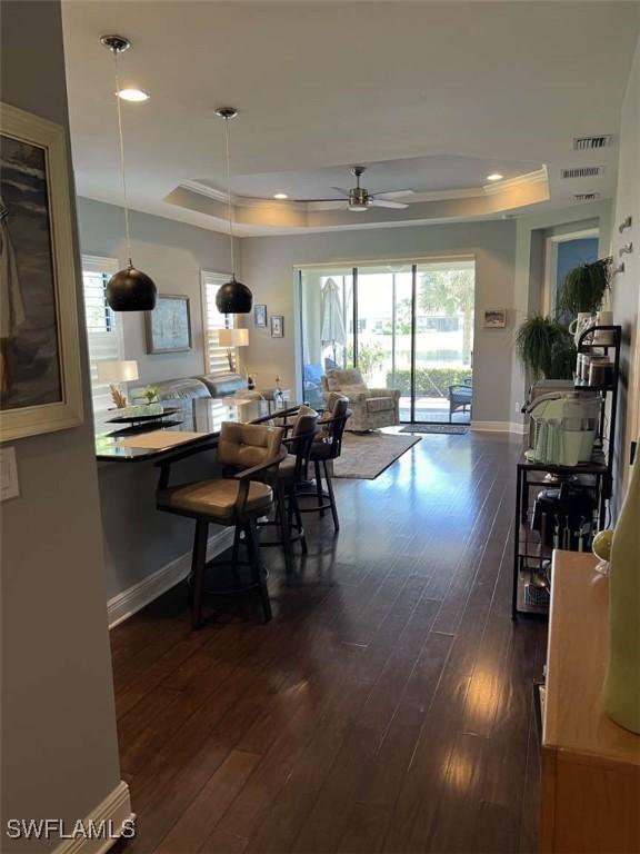 dining area with dark hardwood / wood-style flooring, a tray ceiling, and ceiling fan