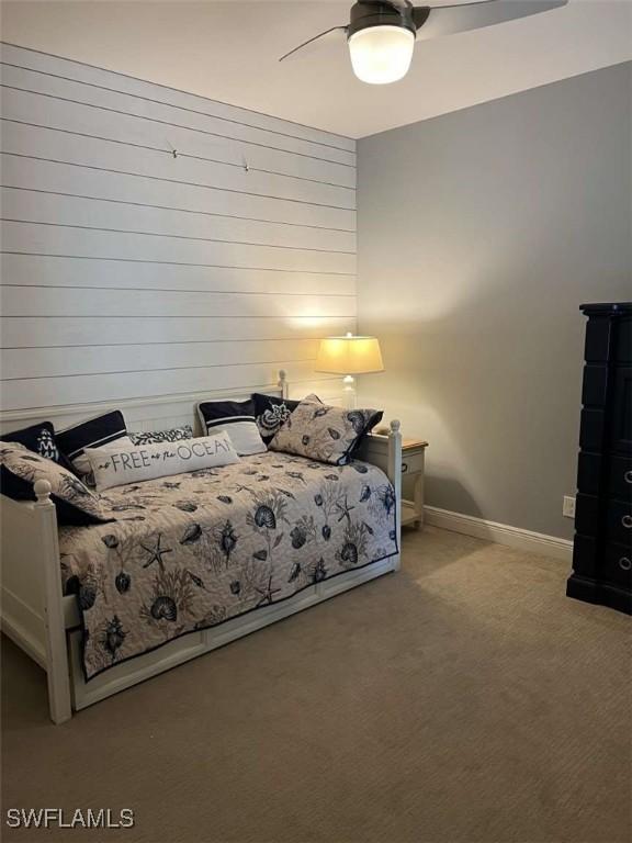 carpeted bedroom with wooden walls and ceiling fan