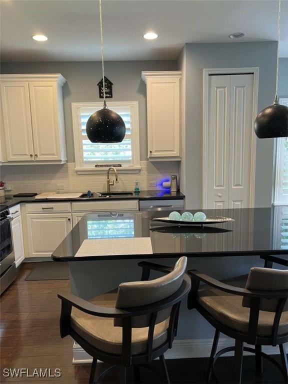 kitchen featuring pendant lighting, dark wood-type flooring, tasteful backsplash, and white cabinets