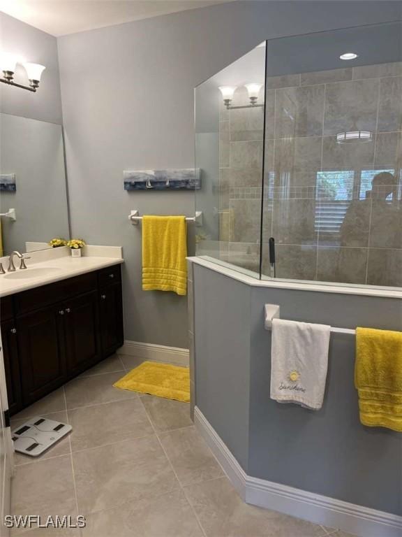 bathroom featuring vanity, tile patterned flooring, and tiled shower