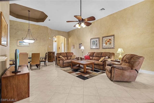 living room with ceiling fan, a raised ceiling, and light tile patterned floors