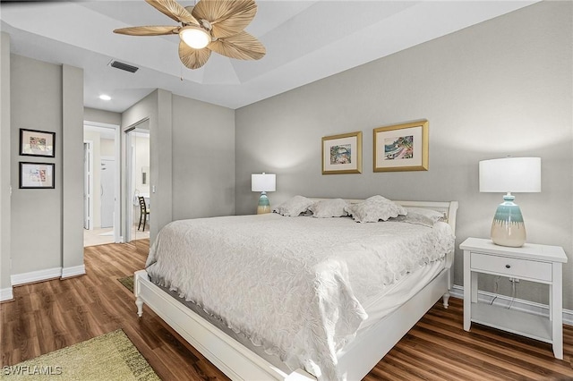 bedroom featuring a tray ceiling, dark wood-type flooring, and ceiling fan