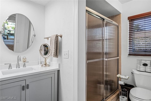 bathroom featuring vanity, a shower with shower door, and toilet