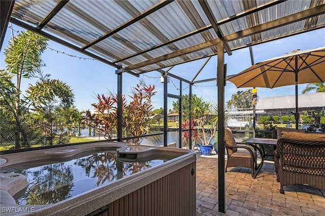 view of patio featuring a hot tub, a water view, and glass enclosure