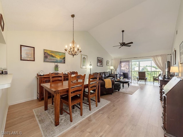 dining room featuring high vaulted ceiling, ceiling fan with notable chandelier, and light wood-type flooring