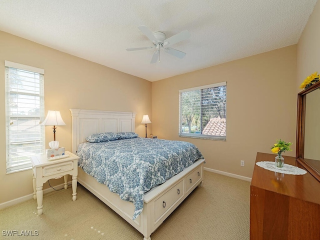 bedroom with multiple windows, light colored carpet, and a textured ceiling