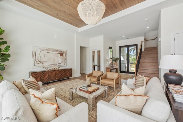 living room with a notable chandelier, wooden ceiling, french doors, and a tray ceiling