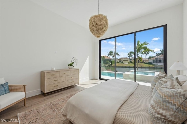 bedroom featuring light hardwood / wood-style flooring, access to outside, and a water view
