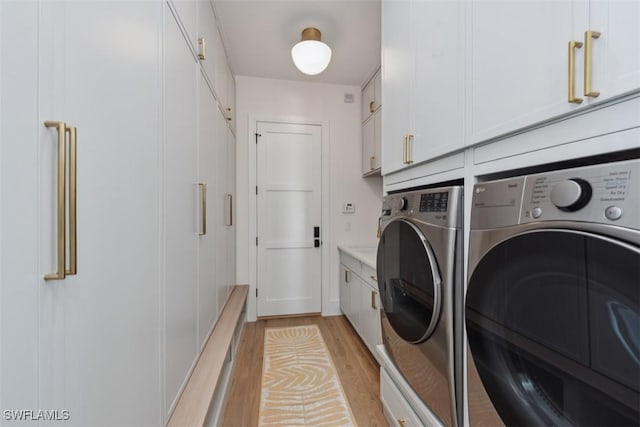 laundry area featuring cabinets, washer and dryer, and light hardwood / wood-style floors