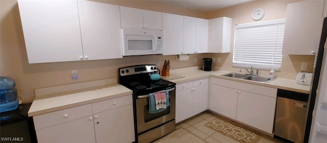 kitchen with light tile patterned floors, appliances with stainless steel finishes, sink, and white cabinets