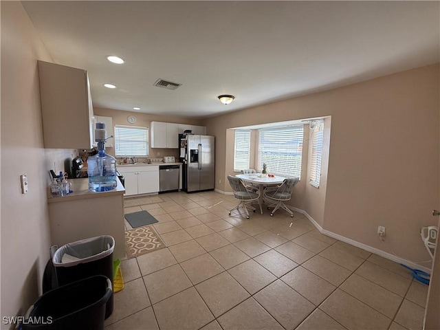 kitchen with stainless steel appliances, light tile patterned flooring, sink, and white cabinets