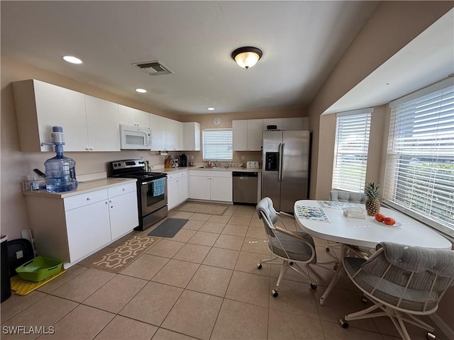 kitchen featuring white cabinetry, sink, light tile patterned flooring, and appliances with stainless steel finishes