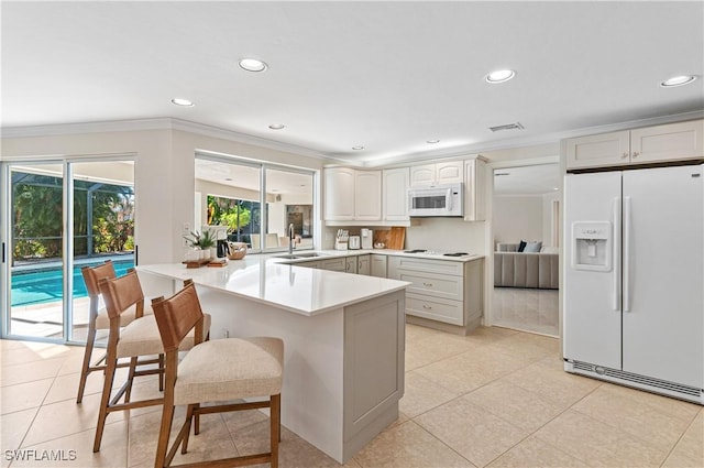 kitchen with sink, a breakfast bar area, white cabinets, kitchen peninsula, and white appliances