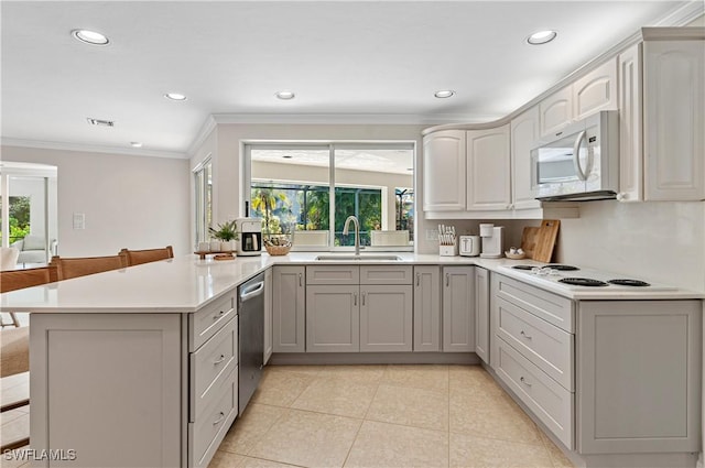 kitchen featuring white appliances, kitchen peninsula, sink, and a wealth of natural light