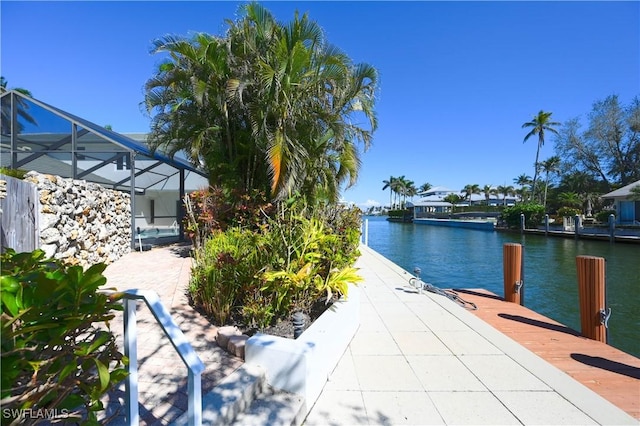 view of patio / terrace with a lanai, a water view, and a dock