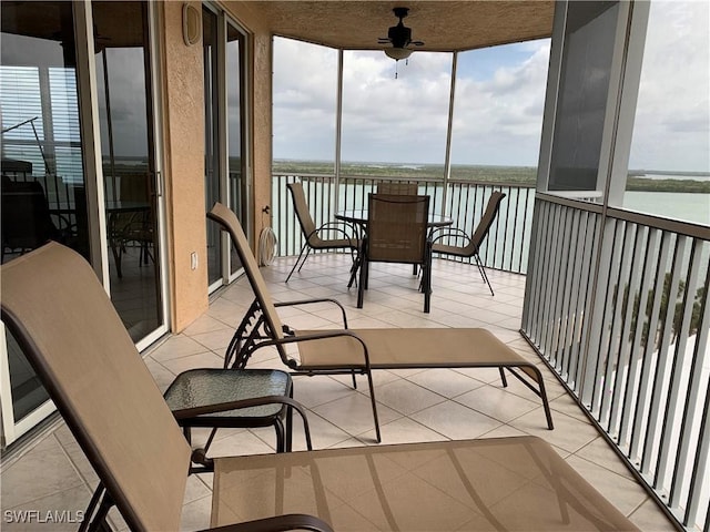 sunroom / solarium with a water view and ceiling fan