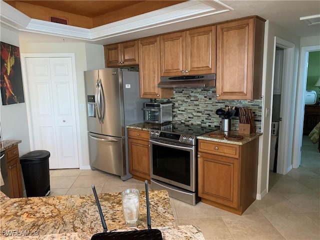 kitchen featuring tasteful backsplash, a raised ceiling, appliances with stainless steel finishes, and light stone counters