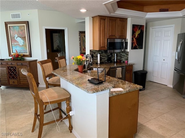 kitchen with sink, a breakfast bar area, fridge, black dishwasher, and light stone counters