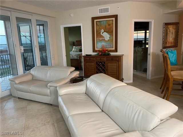 living area featuring light tile patterned floors, baseboards, and visible vents