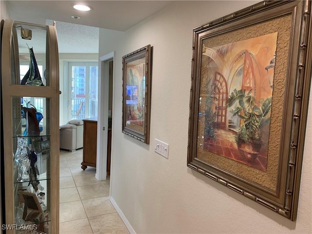 hallway with light tile patterned floors and a textured ceiling