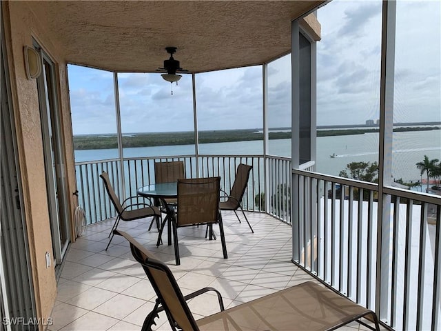 sunroom featuring plenty of natural light, ceiling fan, and a water view