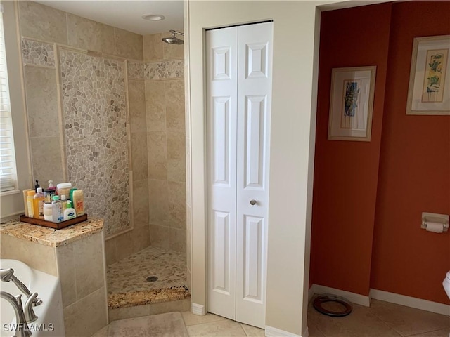 bathroom featuring a closet, tile patterned flooring, a tile shower, and baseboards