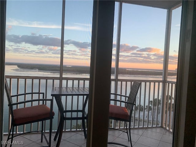 balcony at dusk featuring a water view