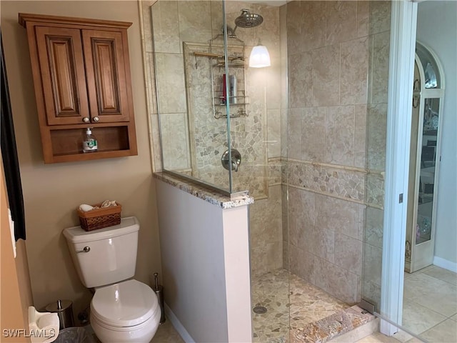 bathroom with toilet, baseboards, and a walk in shower