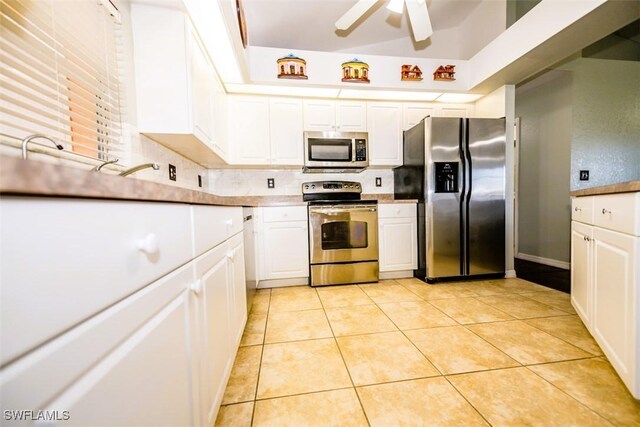 kitchen featuring light tile patterned flooring, appliances with stainless steel finishes, decorative backsplash, and white cabinets