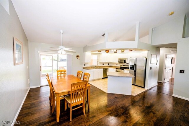 dining area with sink, light hardwood / wood-style floors, and high vaulted ceiling