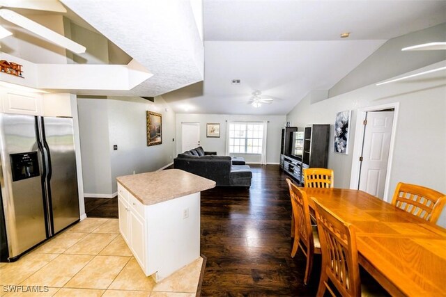 kitchen featuring ceiling fan, white cabinetry, stainless steel refrigerator with ice dispenser, a kitchen island, and vaulted ceiling