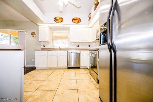 kitchen with light tile patterned flooring, white cabinetry, sink, ceiling fan, and stainless steel appliances