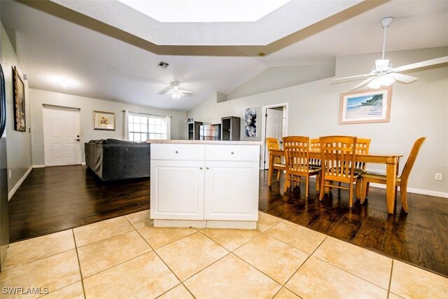 kitchen featuring white cabinetry, vaulted ceiling, light tile patterned floors, and ceiling fan