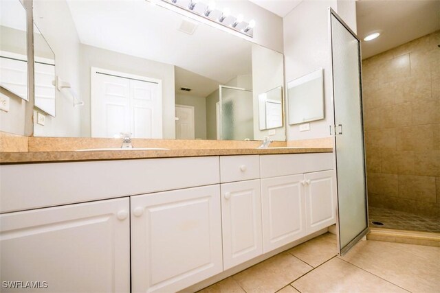 bathroom with tile patterned flooring, vanity, and walk in shower