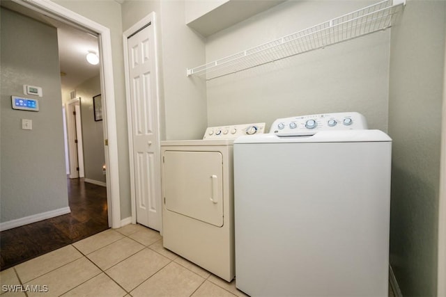 clothes washing area featuring washer and clothes dryer and light tile patterned flooring