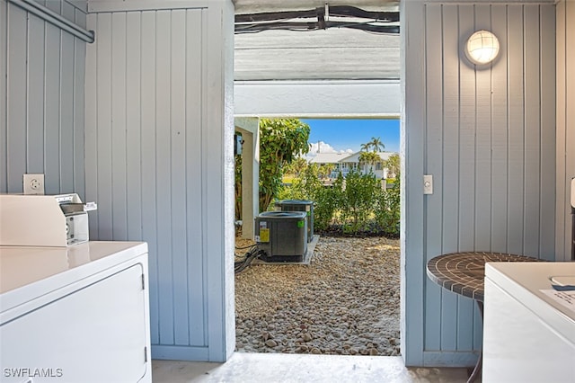 clothes washing area featuring wooden walls and washer and dryer