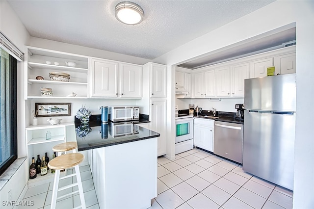 kitchen with stainless steel appliances, sink, white cabinets, and a kitchen breakfast bar