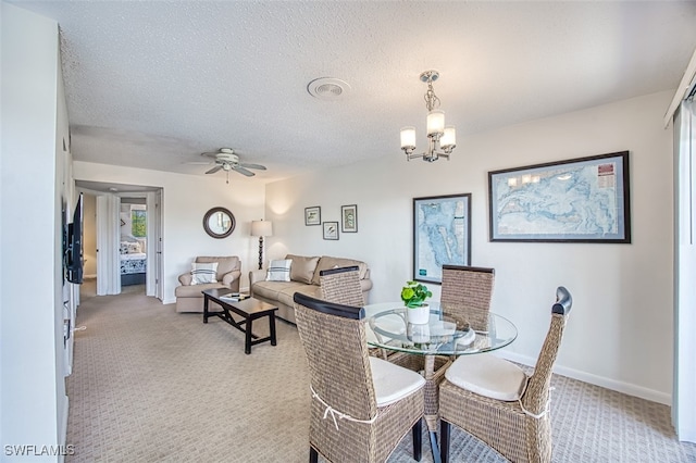 carpeted dining area featuring ceiling fan with notable chandelier and a textured ceiling