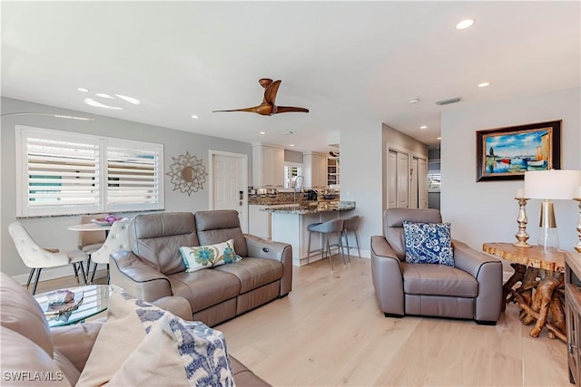 living room with ceiling fan and light hardwood / wood-style flooring