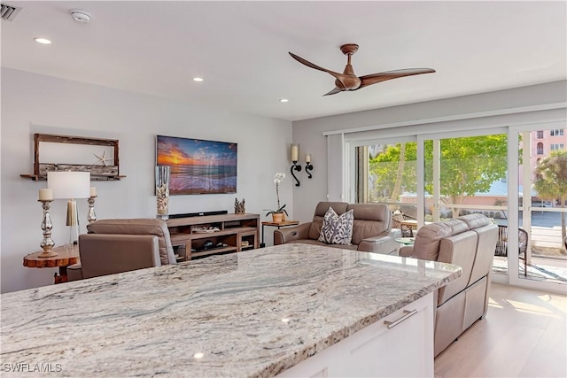 kitchen with white cabinetry, light stone countertops, ceiling fan, and light wood-type flooring