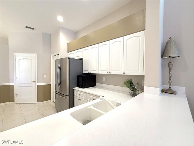 8744 Naples Heritage Dr Unit E28, Naples, FL 34112 - kitchen with sink, light tile patterned floors, stainless steel refrigerator, white cabinets, and kitchen peninsula