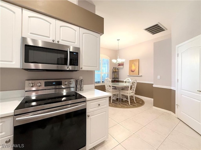 8744 Naples Heritage Dr Unit E28, Naples, FL 34112 - kitchen with light tile patterned floors, appliances with stainless steel finishes, hanging light fixtures, a notable chandelier, and white cabinets