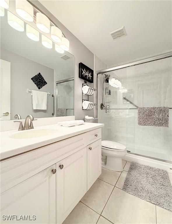 8744 Naples Heritage Dr Unit E28, Naples, FL 34112 - bathroom with tile patterned floors, toilet, a shower with door, and vanity