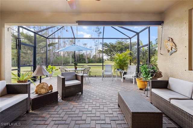 view of patio with ceiling fan, an outdoor hangout area, and glass enclosure