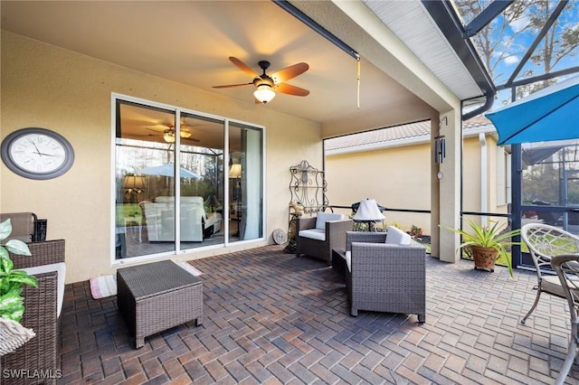 view of patio / terrace featuring ceiling fan, an outdoor living space, and glass enclosure