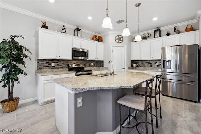 kitchen featuring sink, appliances with stainless steel finishes, light stone counters, an island with sink, and white cabinets