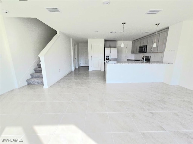 kitchen with hanging light fixtures, kitchen peninsula, gray cabinets, stainless steel appliances, and light stone countertops